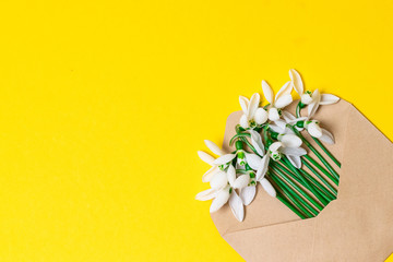 Opened craft paper envelope full of spring blossom flowers on white background. top view.