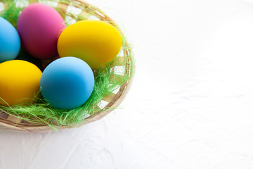 Colorful easter eggs in a wicker basket, on a white background. space for text