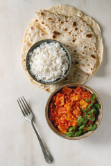 Vegan vegetarian curry with ripe yellow jackfruit served in ceramic bowl with rice, coriander and homemade flatbread flapjack over white marble background. Flat lay, space