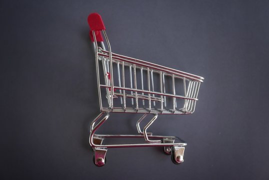 Top View Of Mini Shopping Cart On Grey Vignette Background.