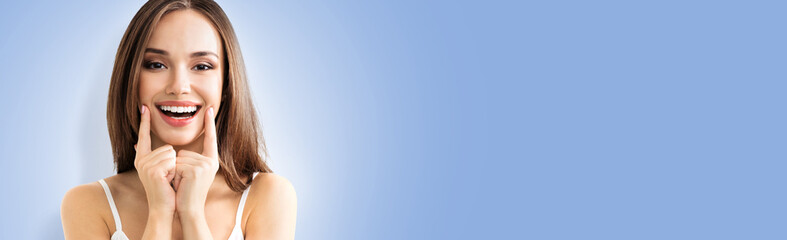 Fototapeta premium young woman showing smile, on blue