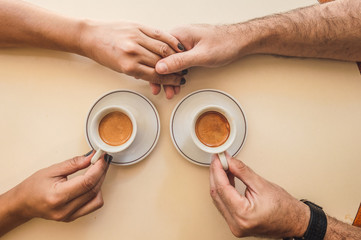 Top view of couple giving hands while they share a coffee