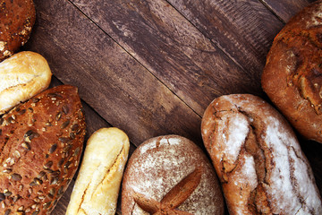 Different kinds of bread and bread rolls on board from above. Kitchen or bakery