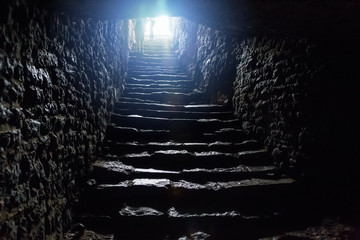 Underground passage under old medieval fortress. Old stone stairs to exit of tunnel
