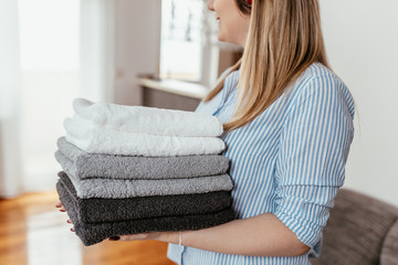 Young woman holding a pile of ironed clean towels.