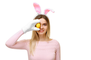 girl with the ears of a hare holds an Easter egg, covering her eye. Isolated on white background. Copy space