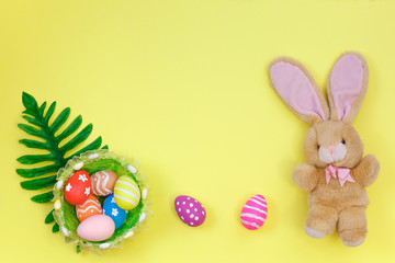 Easter concept. Easter bunny decorative with eggs in basket on yellow background. top view, copy space.E aster Flat lay.