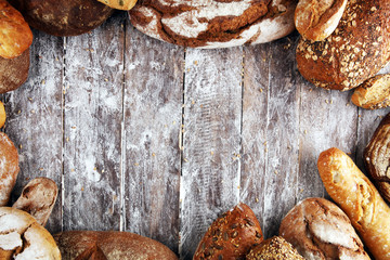 Different kinds of bread and bread rolls on board from above. Kitchen or bakery