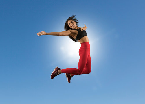 Fit woman jumping with blue sky background