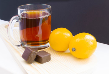 cup of tea with lemon and with chocolate on dark background