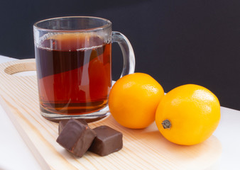 cup of tea with lemon and with chocolate on dark background