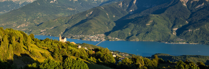 Elevated panoramic view on the Church of the village of Saint-Apollinaire and Savines-Le-Lac at sunset. Summer in the Hautes-Alpes, European Alps, France