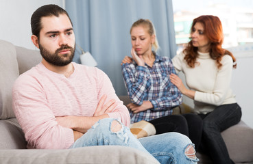Sad man sitting  after quarrel and girl with mother on background