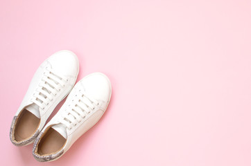 White sneakers on pastel pink background. Flat lay, top view minimal background