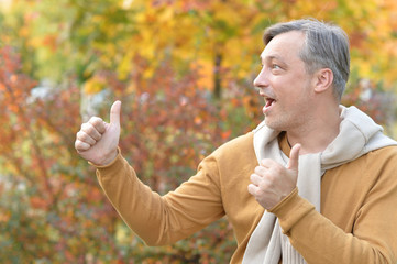 Handsome confident man posing, autumn leaves on background