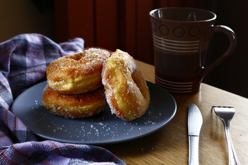 Sugar raised or sugar flavored donuts on a plate and a coffee mug.