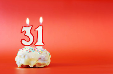 Thirty one years birthday. Cupcake with white burning candle in the form of number 31. Vivid red...