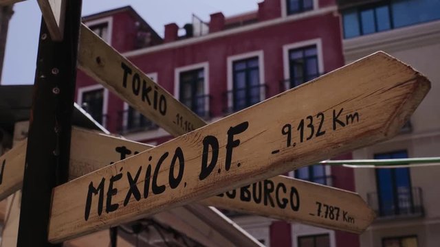 A wooden post with a road sign that points to London, Paris and New York 