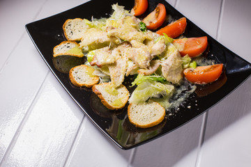 Caesar salad with bacon and quail eggs Black plate