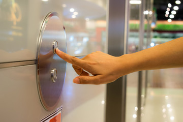 Closeup portrait of a female finger pushing elevator button in the shopping mall.