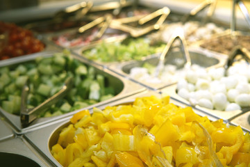 Yellow pepper, cucumbers and other ingredients in a salad bar in a supermarket.