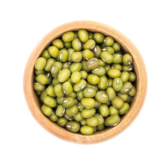 Mung beans in a small wooden bowl seen directly from above and isolated on white background