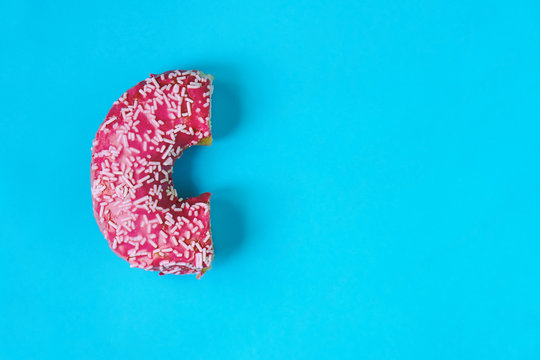Half of a donut lying on the blue paper background