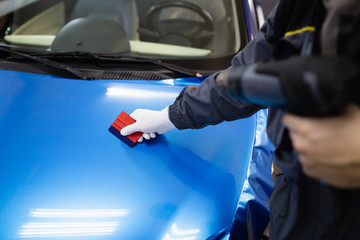 Car wrapping specialist putting vinyl foil or film on car. Selective focus.