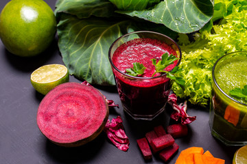 Healthy drink with fruits and vegetables on the black wooden background.