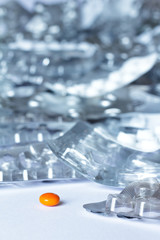 One single pill in front of many empty sheets on white background, drug misuse concept