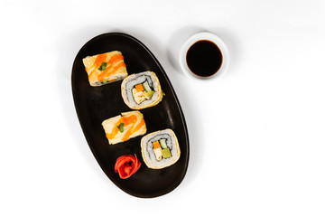 The concept of Japanese and Chinese cuisine. Sushi rolls laid out on a plate and soy sauce.