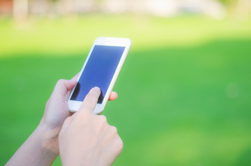 hipster woman using mobile phone touching screen at outdoor, hands typing smart phone texting messaging lifestyle working app device technology internet social data online concept on green background.