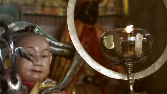Oil lamp in chinese shrine. Close up of oil lamp burns hanging in front of altar table and god statue at Jui Tui shrine Phuket,hd slow motion.