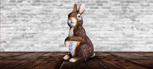 Rabbit on a wooden table against a background of a brick wall.