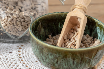 Sunflower seeds in a green bowl, on a wooden background