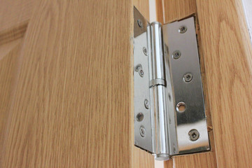 Door hinge close up view on wooden surface. House interior detail of modern simple door