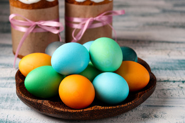 Multicolored Easter eggs on a plate and Easter cakes in the background