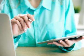 Business woman looking and studying statistics on tablet display closeup. Female left hand holds pen, right holds tablet.