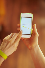 Closeup on phone screen with fit app in hand of healthy woman