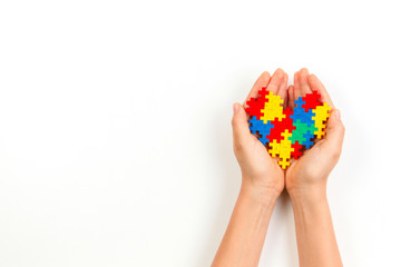 Child hand holding colorful heart on white background. World autism awareness day concept