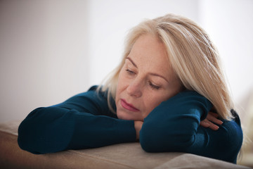 Sad woman sitting on a sofa in the living room