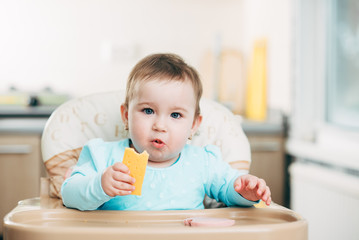 Little girl in a high chair eating cheese
