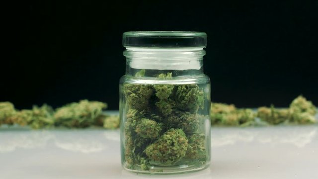 A Cannabis jar reveals through a dolly-in movement. 2 takes,