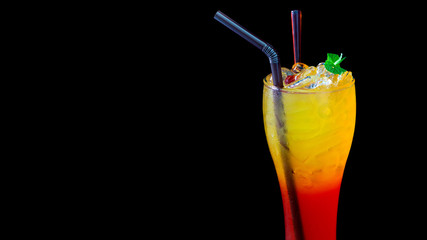Tropical orange and yellow cocktail with ice on black background.