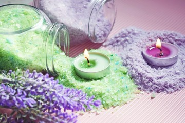 Obraz na płótnie Canvas Lilac and green bath salt and candles on pink background.