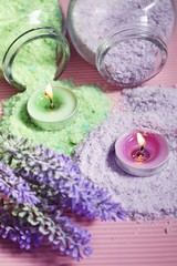 Obraz na płótnie Canvas Lilac and green bath salt and candles on pink background.