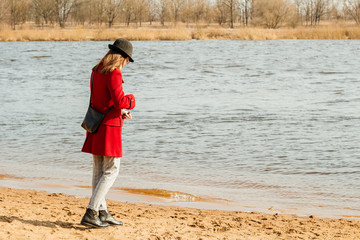 A young girl walks along the river. Spring mood