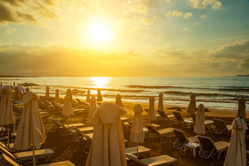Sunset with the sun on background of clouds on the beach. Crete, Greece.