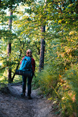 Fototapeta na wymiar Young woman hiker with backpack walking in forest during summer vacation trip
