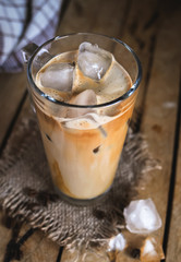 Close-up of ice coffee in a glass on wooden background 